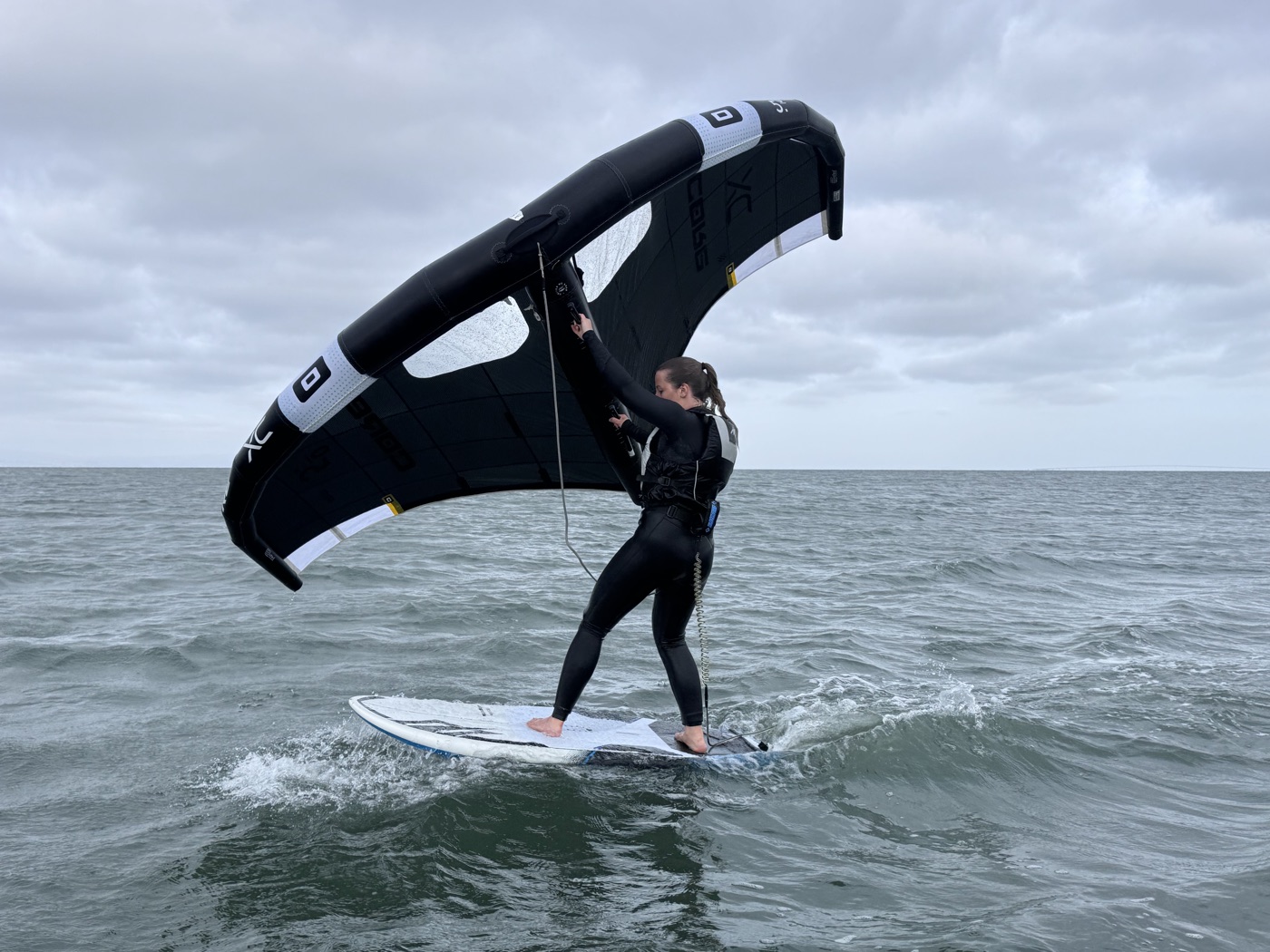 Isabella wing foiling, holding the wing overhead on open water